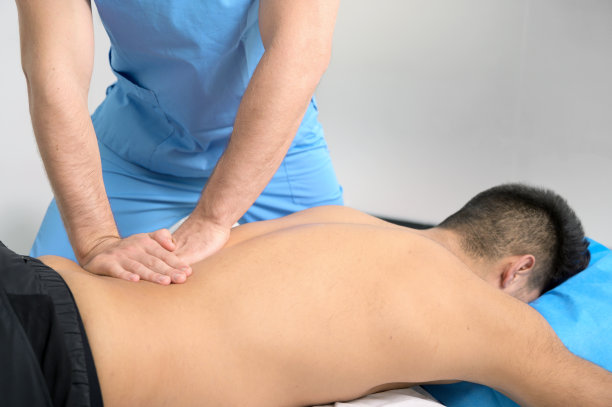 理疗师在运动康复诊所为年轻运动员按摩背部。高质量的照片图片下载