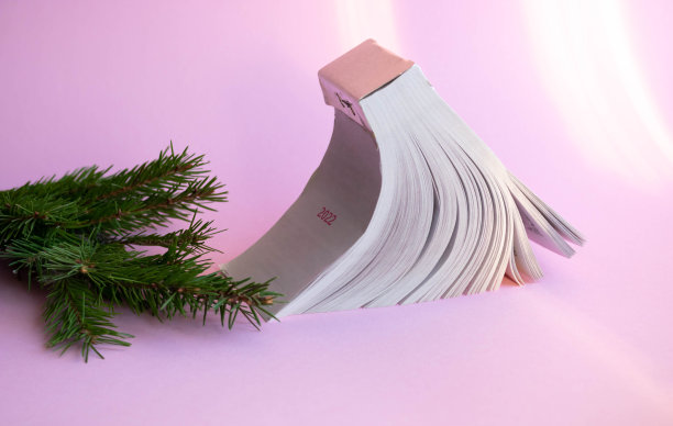 一个新的撕掉的日历，粉红色的背景上有一小枝云杉图片下载