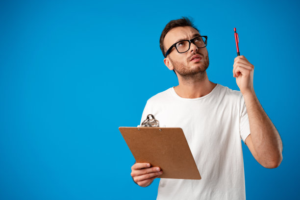 年轻男子在写字板上做笔记的肖像，蓝色的背景图片下载