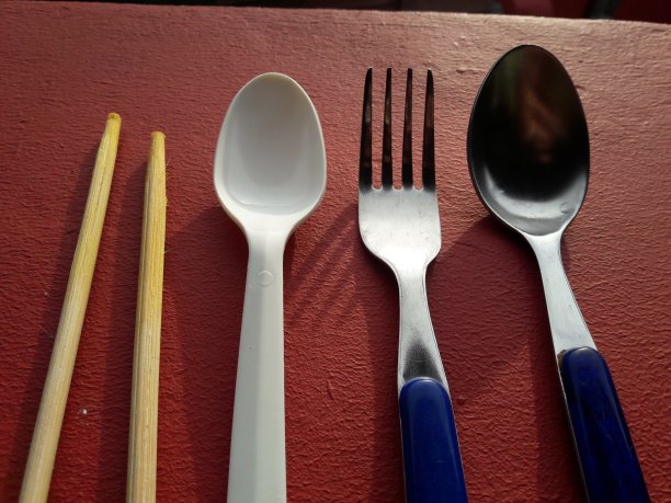 把叉子、勺子和筷子放在红色背景的桌子上图片下载