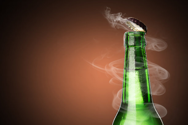 一瓶冰镇的饮料，滴在瓶子里。啤酒瓶盖的开启与气体输出。图片下载