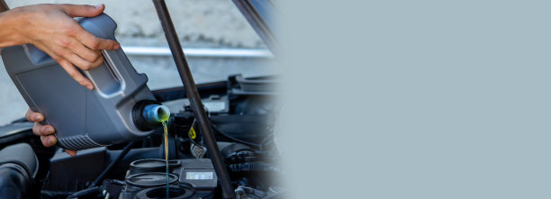 一个汽车修理工给汽车换机油，把油倒进汽车发动机。图片下载