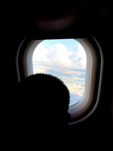 男孩向飞机窗外望去图片下载