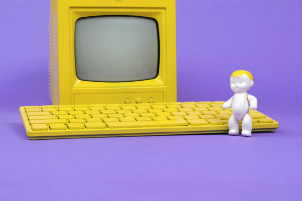 黄色键盘和黄色显示器旁边有一个婴儿雕像。图片下载