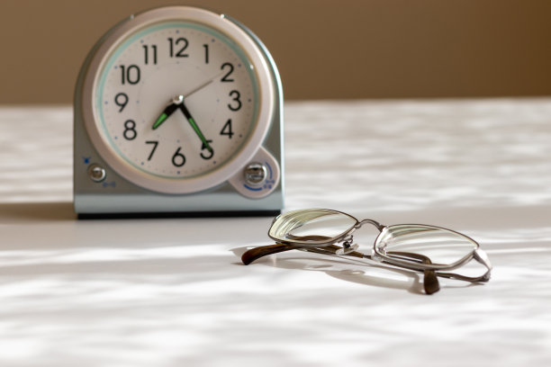 白色的桌子上放着眼镜和时钟图片下载