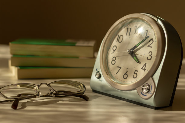 晚上在靠窗的桌子上放着眼镜、钟表和书图片下载