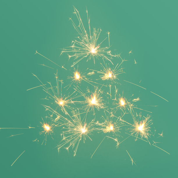 由洒水器在绿色背景上发出火花的创意圣诞树。最小的新年概念。图片下载