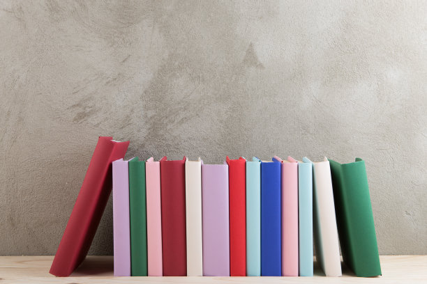 教育与阅读理念——木桌上的一组彩色书籍，混凝土墙的黑板图片下载