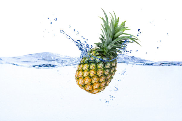 菠萝落在清澈的蓝色水飞溅与泡沫孤立在白色的背景。图片下载