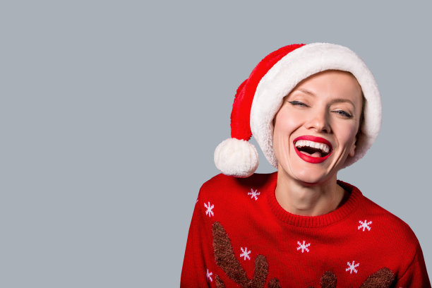穿着红色毛衣，戴着圣诞老人帽子的漂亮圣诞老人女人图片下载