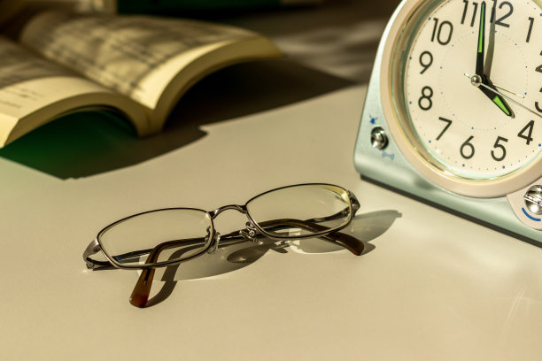晚上在靠窗的桌子上放着眼镜、钟表和书图片下载