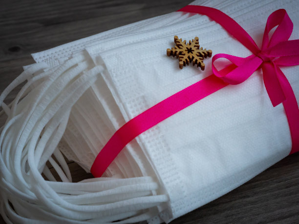 医用口罩作为礼品，用紫丝带系上，以木片装饰为背景图片下载