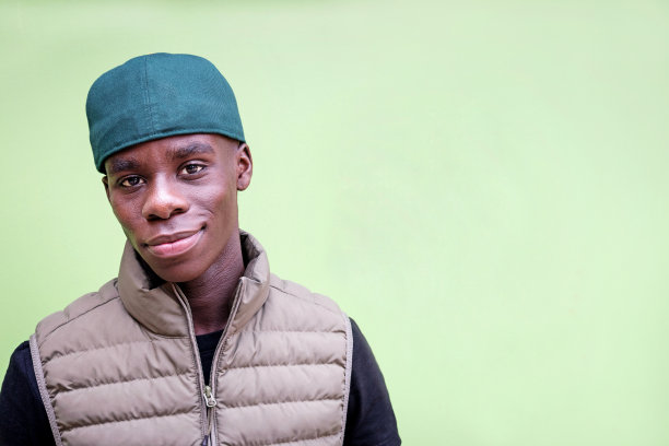 时髦的非洲人在绿色背景下看相机素材图片