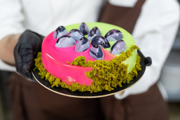 特写的糖果师的手，一个男人和一个女人拿着一个蛋糕。图片下载