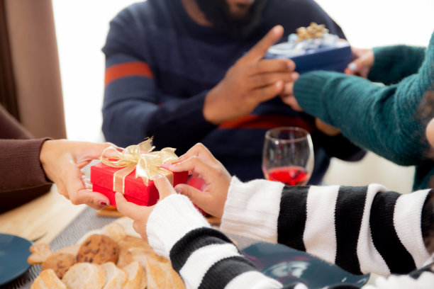 幸福的家庭与女儿赠送礼品盒与父母在家里晚餐，庆祝在圣诞节与孩子惊喜父母在家里享受，感恩节前夕，圣诞快乐。图片下载