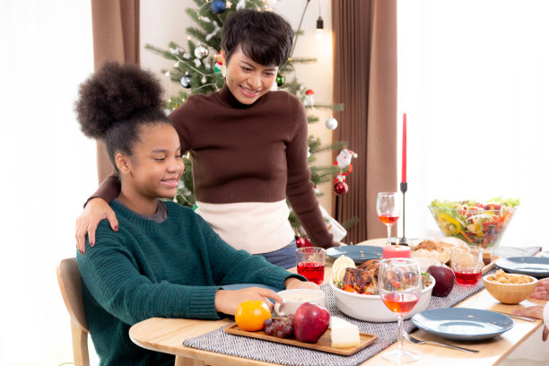快乐的非洲家庭与母女在节日的感恩节前夕一起在家里吃大餐，在圣诞节和新年装修时举行庆祝会，在节日里关系亲密。图片下载