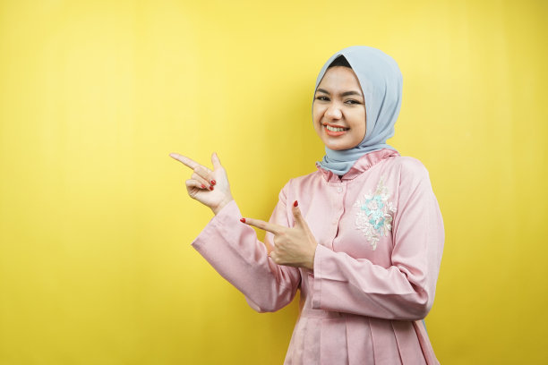开朗美丽的年轻穆斯林妇女，用手指着空荡荡的空间，推销着什么，与世隔绝图片下载
