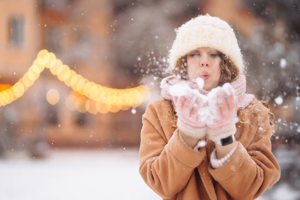 快乐的女人在花环灯光的背景下，穿着冬季风格的衣服。图片下载