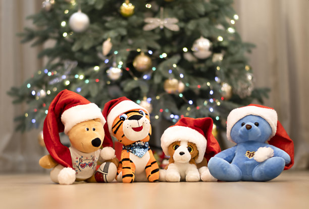 圣诞老人帽子里的毛绒玩具坐在圣诞树下图片下载