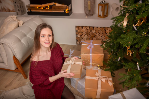 圣诞快乐，节日快乐!一个年轻漂亮的女孩在新年前夜拿着一盒礼物。图片下载