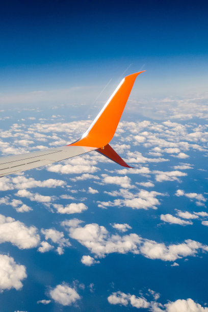 惊人的观点。一架小型定时飞机的机翼映衬着蓝天，下面是海面上的云朵。从舷窗看。期待已久的假期、休息和旅游理念。特写,俯视图图片下载