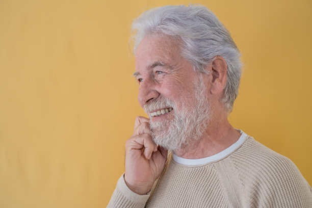 照片上美丽的老人与白胡子和头发看着相机微笑在黄色的背景图片下载