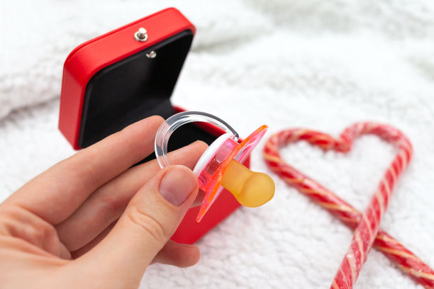 女人的手从一个红色的礼品盒里拿了一个粉色的奶嘴图片下载