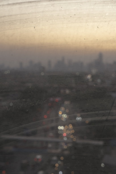 傍晚日落时分，从肮脏的窗口看到雅加达城的剪影图片下载