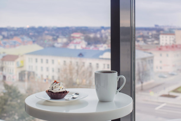 在咖啡厅靠窗的白色桌子上的纸杯蛋糕图片下载