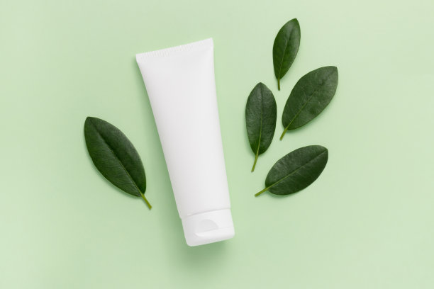白色模型管面霜或洗液与鲜绿叶顶部视图在浅绿色的背景图片下载