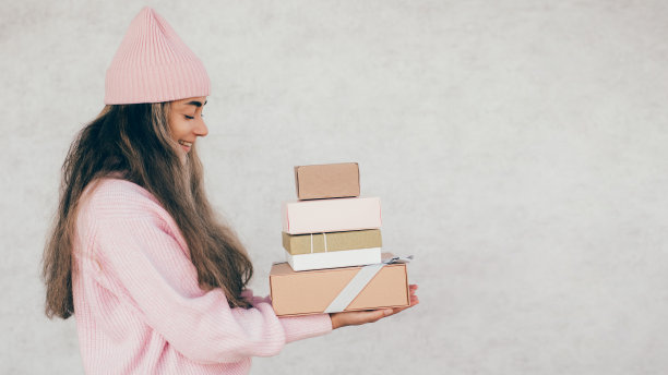 年轻快乐的女人拿着纸袋和盒子。图片下载