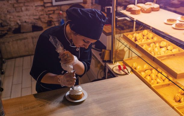 一个糕点师女孩用装着蛋白质奶油的糕点袋装饰酥饼蛋糕，把奶油挤出来。特写镜头图片下载