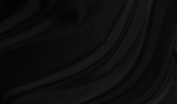 黑灰色绸缎深色织物纹理豪华闪亮，是抽象的丝绸布背景图案柔和的波浪模糊美丽。图片下载