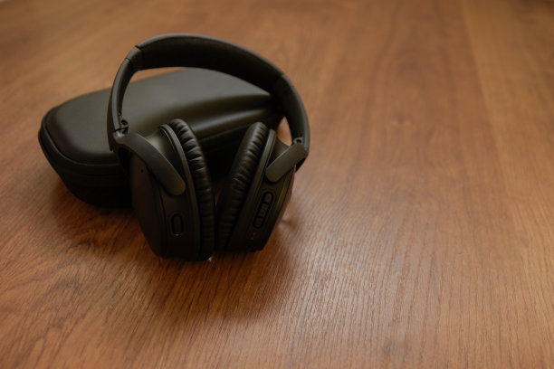 黑色无线蓝牙耳机休息在黑色外壳上的木地板-前左低视图图片下载