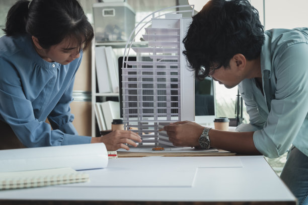 工程师和建筑师女性讨论建筑设计的概念。在设计师办公室用建筑模型进行建筑工程估算。选择性聚焦中心图像。图片下载