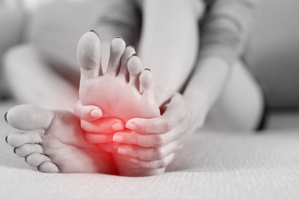 一个女人坐在家里的沙发上感到膝盖疼痛。用手按摩她疼痛的膝盖。保健和医疗理念。图片下载