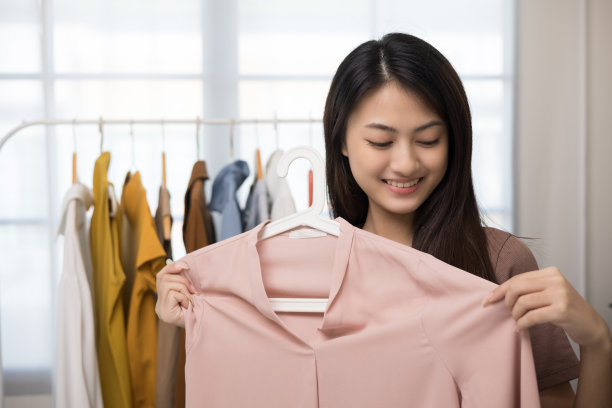 亚洲女性选择许多衣服挂在栏杆和试衣服。一位妇女在时装店买衣服。在商店寻找t恤或连衣裙和合适的尺寸图片下载