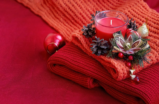 圣诞节静物生活场景。季节性的照片。蜡烛，松果，圣诞球编织红色的背景。红色背景。图片下载