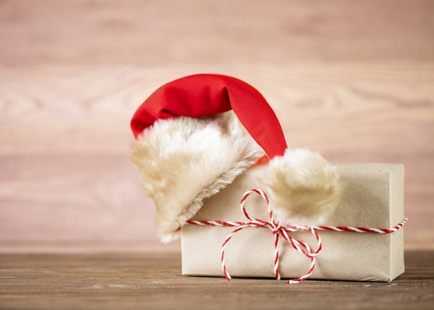 圣诞贺卡礼物在牛皮纸与圣诞老人的锄头在木制背景上。图片下载