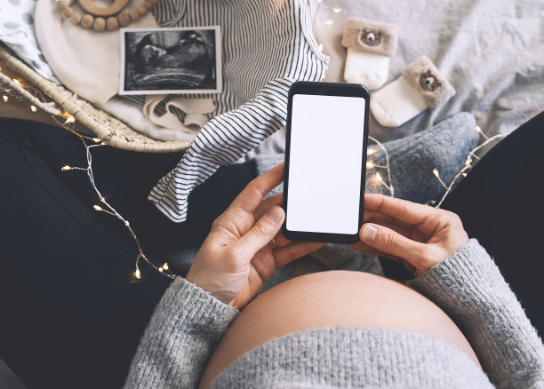 孕妇手里拿着空白显示的智能手机。孕妇腹部特写与超声波照片及医学检查报告。图片下载