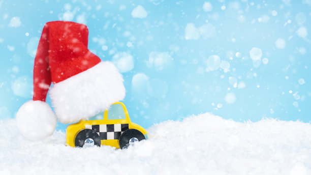 横幅。戴着圣诞老人帽子的黄色出租车在蓝色背景的雪地上行驶。圣诞贺卡。新年出租车在雪堆里。新年的概念。副本的空间。图片下载