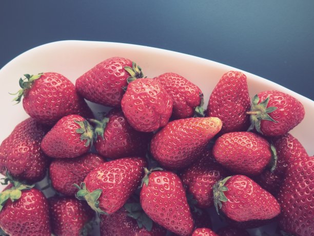 盘子上的草莓，灰色背景。白色的盘子和美味的红色大草莓。健康食物，维生素和素食。还有食物的静物。副本的空间。平躺图片下载