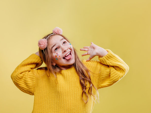 有趣的十几岁的女孩，脸上有贴纸，戴着粉红色的毛绒绒的头罩图片下载