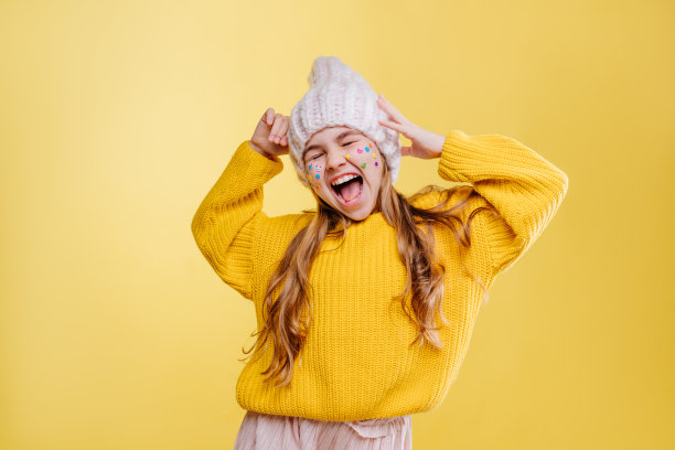 可爱的十几岁女孩与贴纸在她的脸在黄色的背景摆姿势图片下载