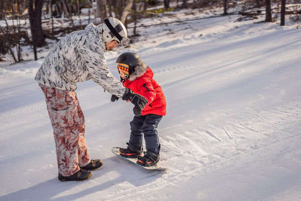 爸爸教儿子滑雪。冬季儿童活动。孩子们的冬季运动。生活方式图片下载
