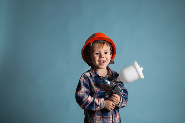 可爱的小白种人戴着安全帽拿着电动喷枪图片下载