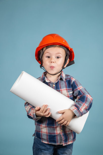 可爱的小男孩建筑工人的肖像在安全帽持有施工图图片下载
