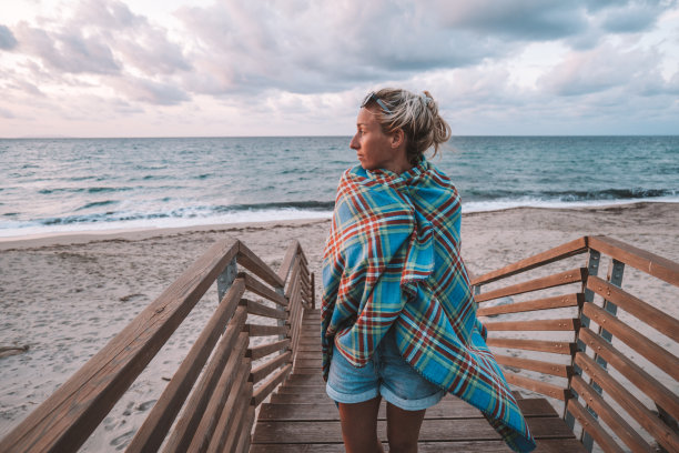 年轻女子在海边沉思日落，独自在海滩上放松散步图片下载