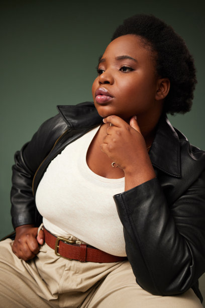 一个漂亮的年轻女子在绿色背景下摆姿势的工作室拍摄图片下载