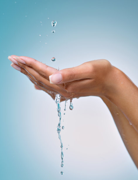 裁剪的镜头，一个无法辨认的女人在工作室的蓝色背景下用手抓水图片下载